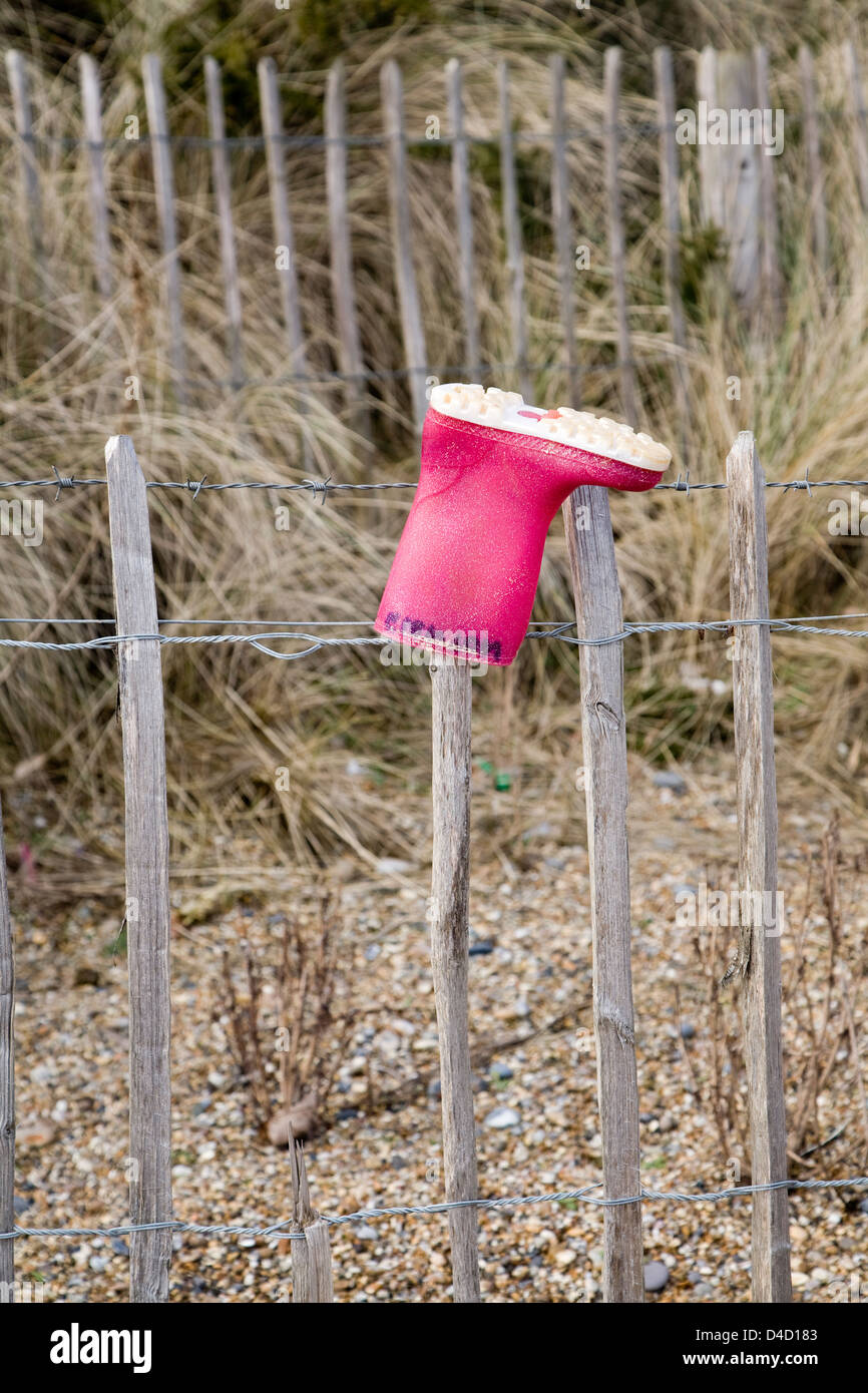 Perso il colore rosso del bambino wellington boot sul palo da recinzione, Dunwich, Suffolk, Inghilterra Foto Stock