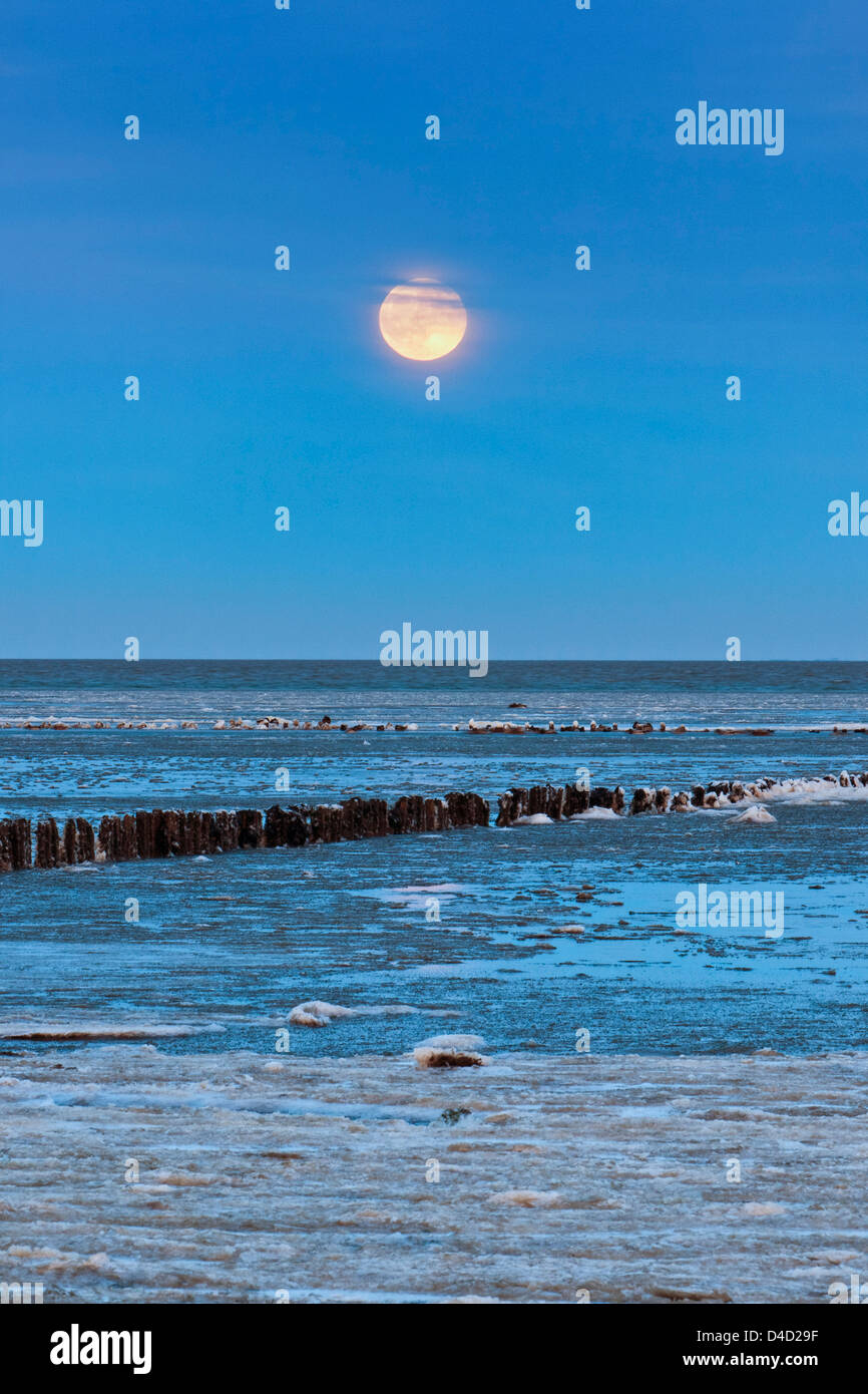 Luna piena al di sopra del mare di Wadden ricoperta di ghiaccio floes in Keitum, Sylt, Germania Foto Stock