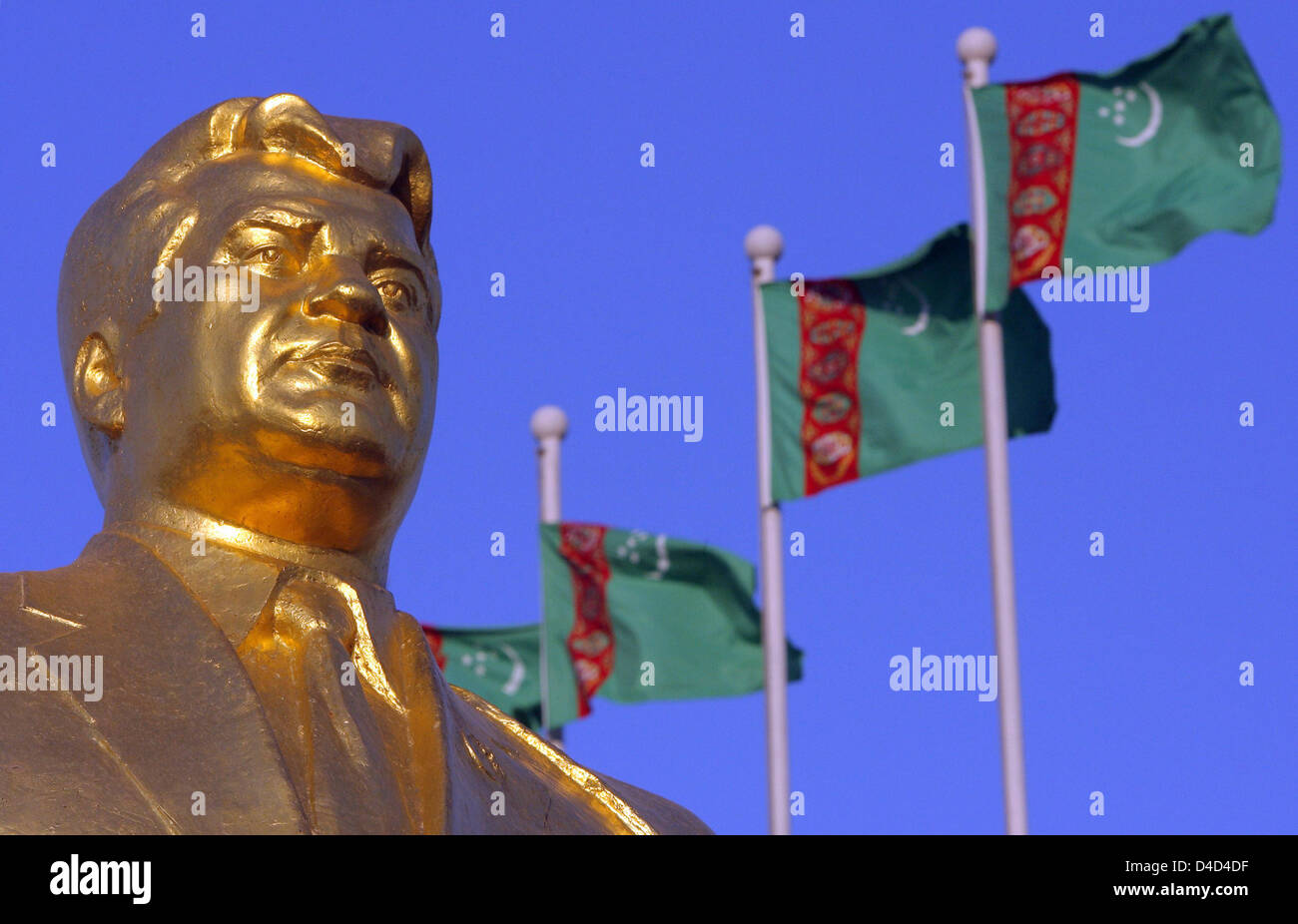 Bandiere turkmeno in onda il vento dietro uno dei tanti golden statue dell ex Presidente turkmeno per la vita, Saparmurat Niyazov nel capitale Aşgabat, Turkmenistan, 25 febbraio 2008. Niyazov morto nel dicembre 2006, aveva il suo popolo adorarlo come Türkmenbaşy il significato di "Padre del Turkmeni'. Foto: Tim Brakemeier Foto Stock