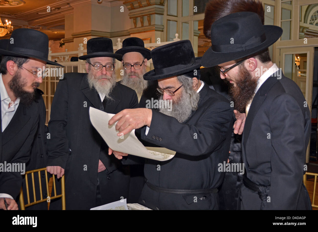 Un Ortodosso Ebrei religiosi lo sposo, destra, legge il suo contratto di matrimonio, il katubah, con la famiglia e gli anziani. Foto Stock