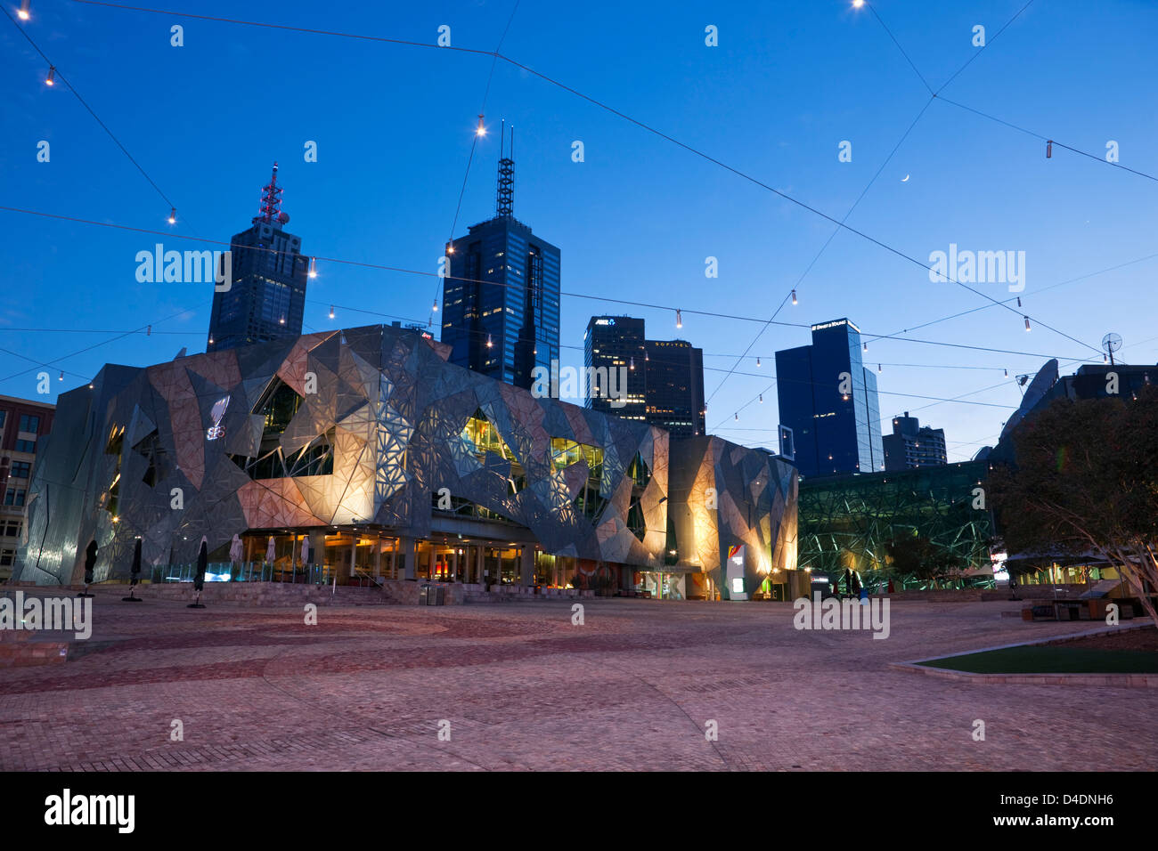 Federation Square illuminato al crepuscolo con lo skyline della città in background. Melbourne, Victoria, Australia Foto Stock