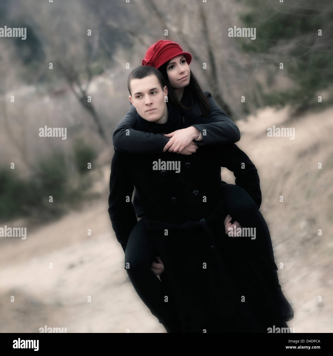 Un uomo porta la sua fidanzata pickaback attraverso una foresta Foto Stock