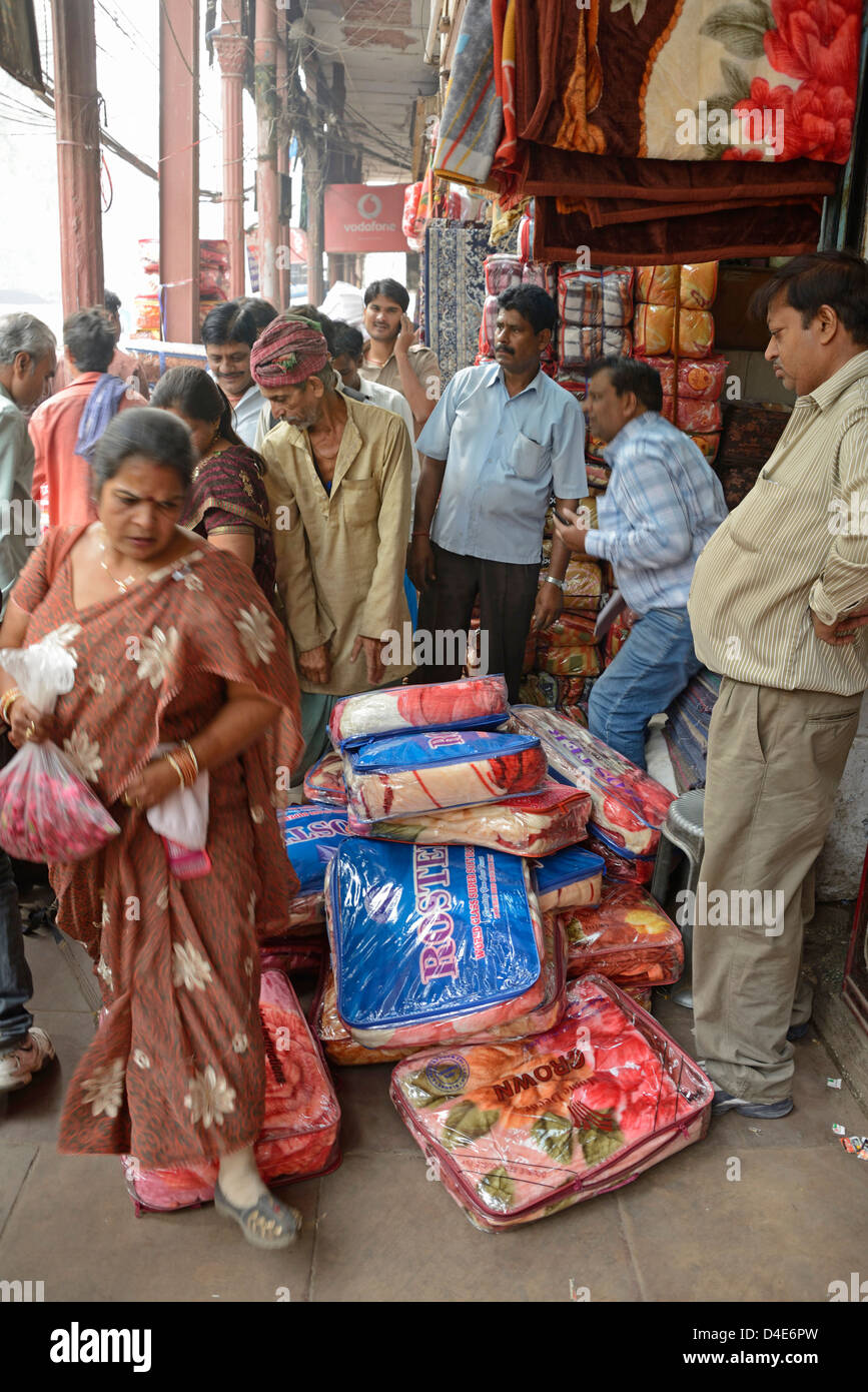 Gli acquirenti si intrecciano intorno alle merci spruzzate su una strada a Shahjahanabad, Chandni Chowk, Old Delhi, India Foto Stock