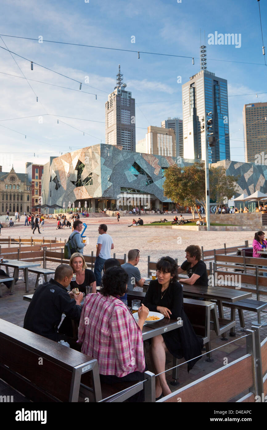 Persone rilassante presso il bar in Federation Square con lo skyline della città in background. Melbourne, Victoria, Australia Foto Stock