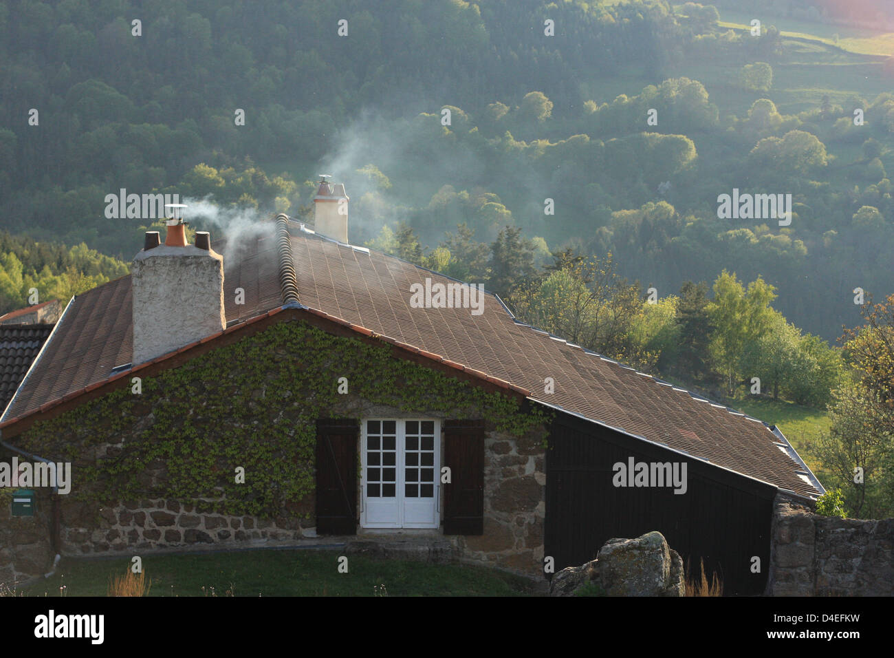Un cottage nella campagna francese, fumo emergente dal camino Foto Stock
