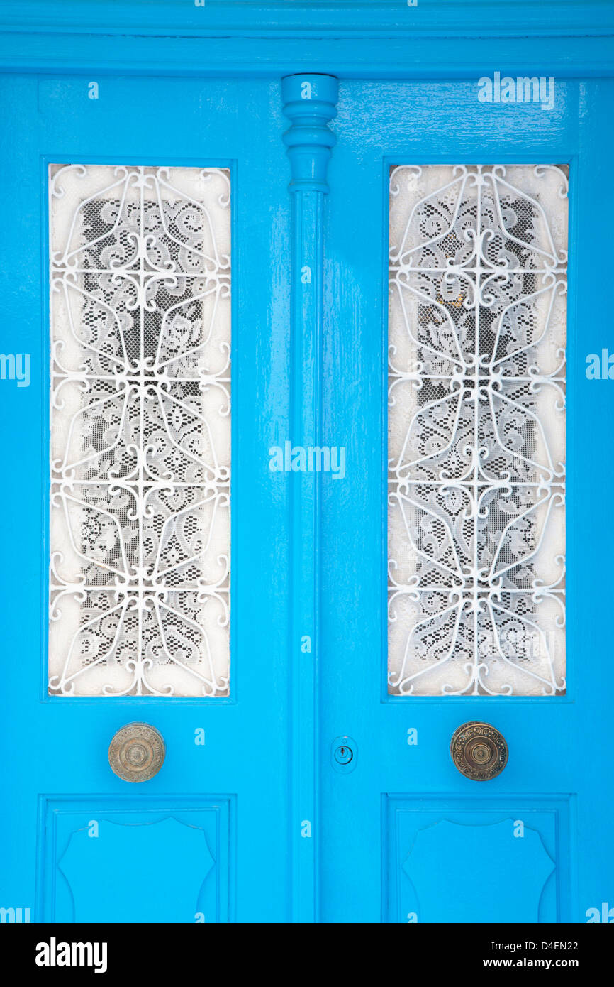 Porte blu con tende di merletto bianco sopra le finestre a Chora (città di Mykonos) sull'isola di Mykonos, Grecia Foto Stock