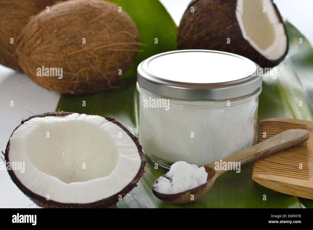 Noci di cocco e organici di olio di noce di cocco in un vasetto di vetro su sfondo bianco. Il trattamento dei capelli. Foto Stock