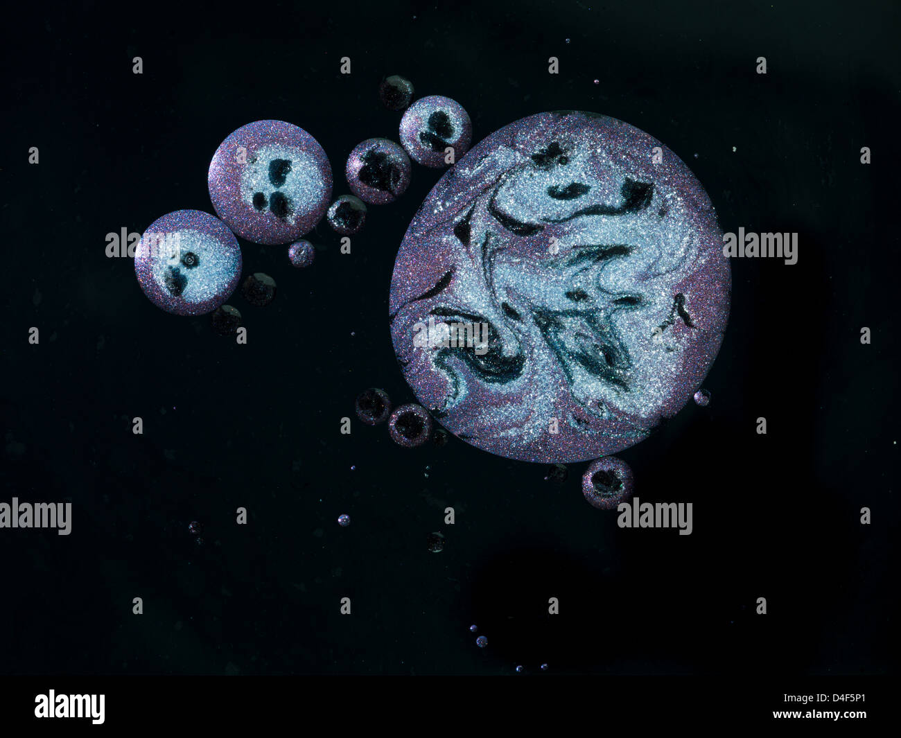 Macro di più di colore porpora gocce di olio con argento e nero inserzioni, su sfondo nero Foto Stock