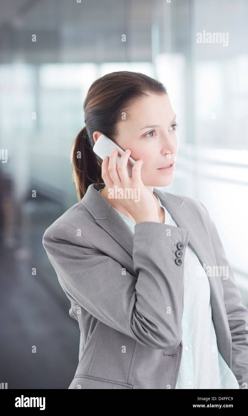 Imprenditrice parlando al cellulare nel corridoio di office Foto Stock