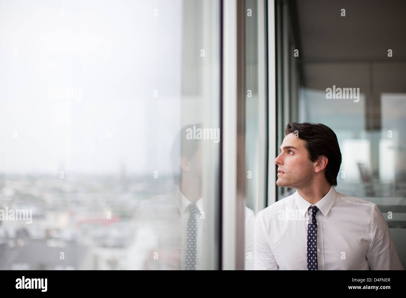 Imprenditore a guardare fuori dalla finestra di ufficio Foto Stock