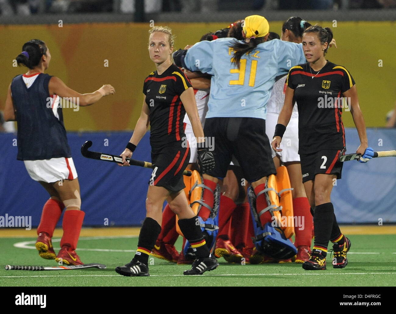 Sconsolato Mandy Haase (L) e Tina Bachmann dalla Germania a piedi passato aflock di celebrare gli operatori cinesi che hanno vinto la semifinale partita Germania contro la Cina nel campo womenÒs Hockey concorrenza ai Giochi Olimpici di Pechino 2008, Pechino, Cina, 20 agosto 2008. Foto: Peer Grimm dpa ###dpa### Foto Stock