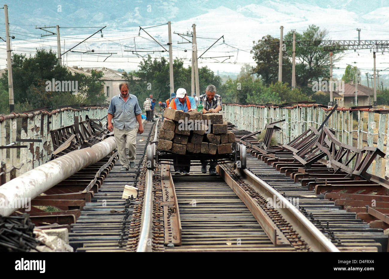 Georgian i lavoratori del settore ferroviario spingere un carro caricato con traversine per la riparazione di un ponte sul fiume Kvari, Georgia, Mercoledì, 20 agosto 2008. Russo gli ingegneri di combattimento utilizzato esplosivi distrutto il link, il taglio di tutto il traffico tra la capitale Tbilisi e la costa del Mar Nero. Foto: Stefan Korshak Foto Stock