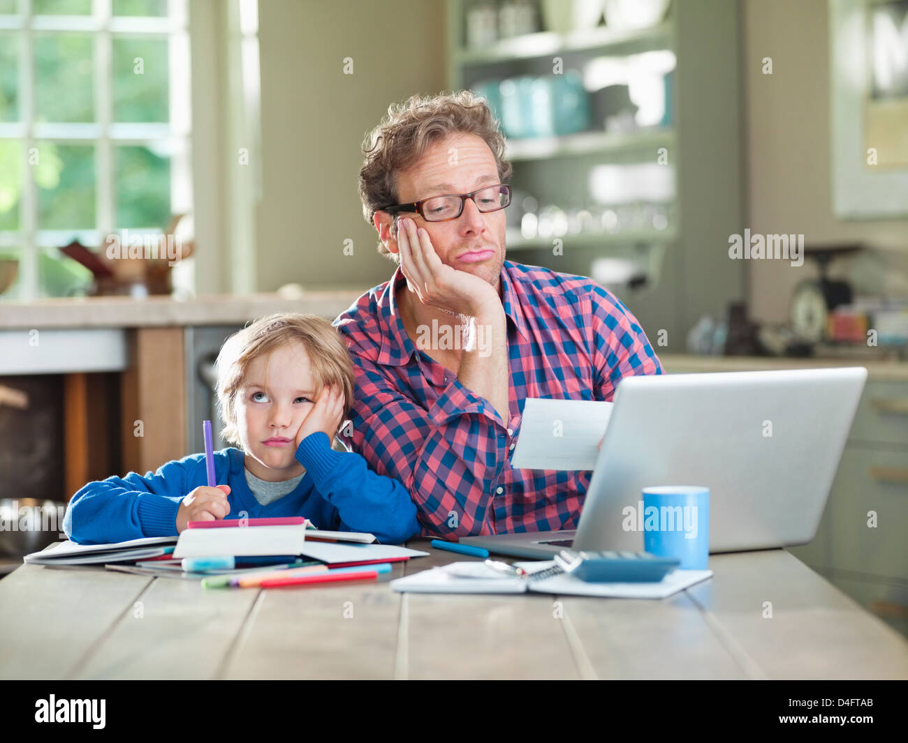 Annoiato padre e figlio lavora a tavola Foto Stock