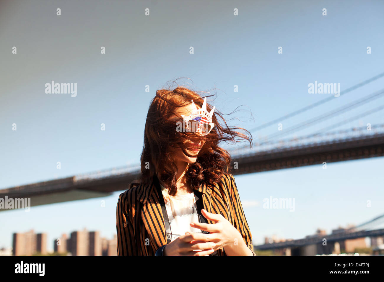 Donna in novità di occhiali da sole dal paesaggio urbano della città Foto Stock