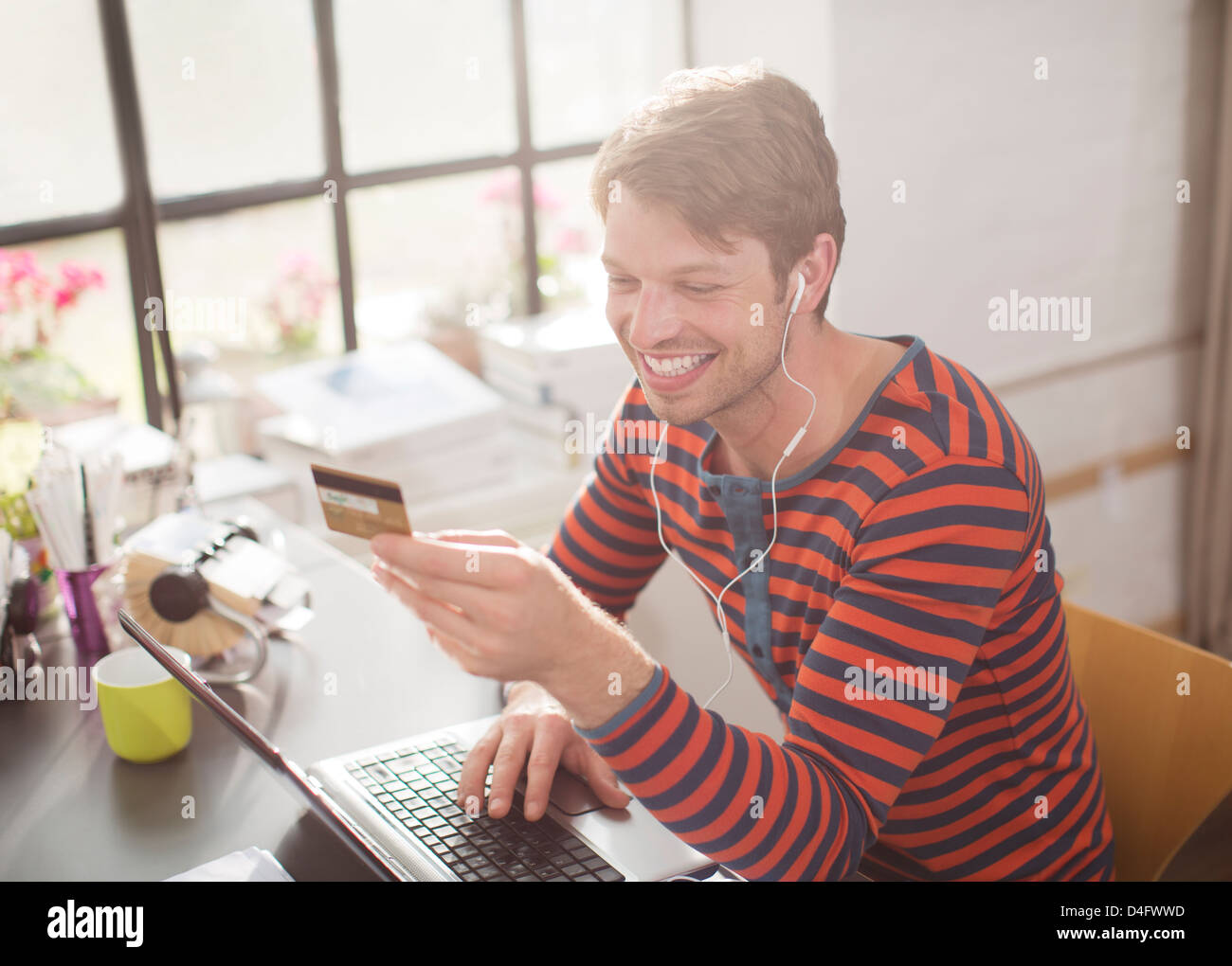 L'uomo nelle cuffie shopping sul computer portatile Foto Stock