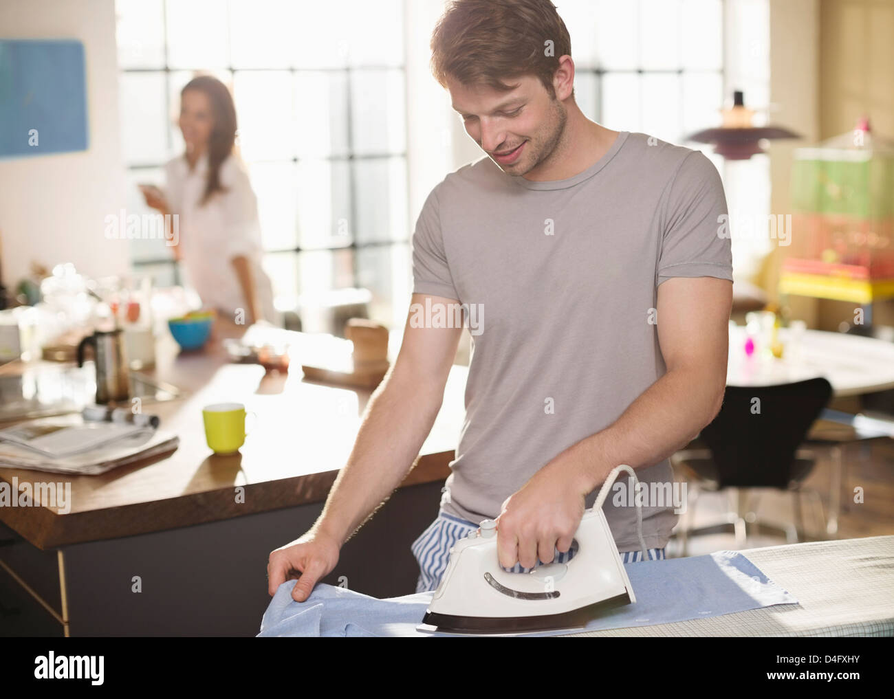 Uomo maglietta di stiratura in cucina Foto Stock