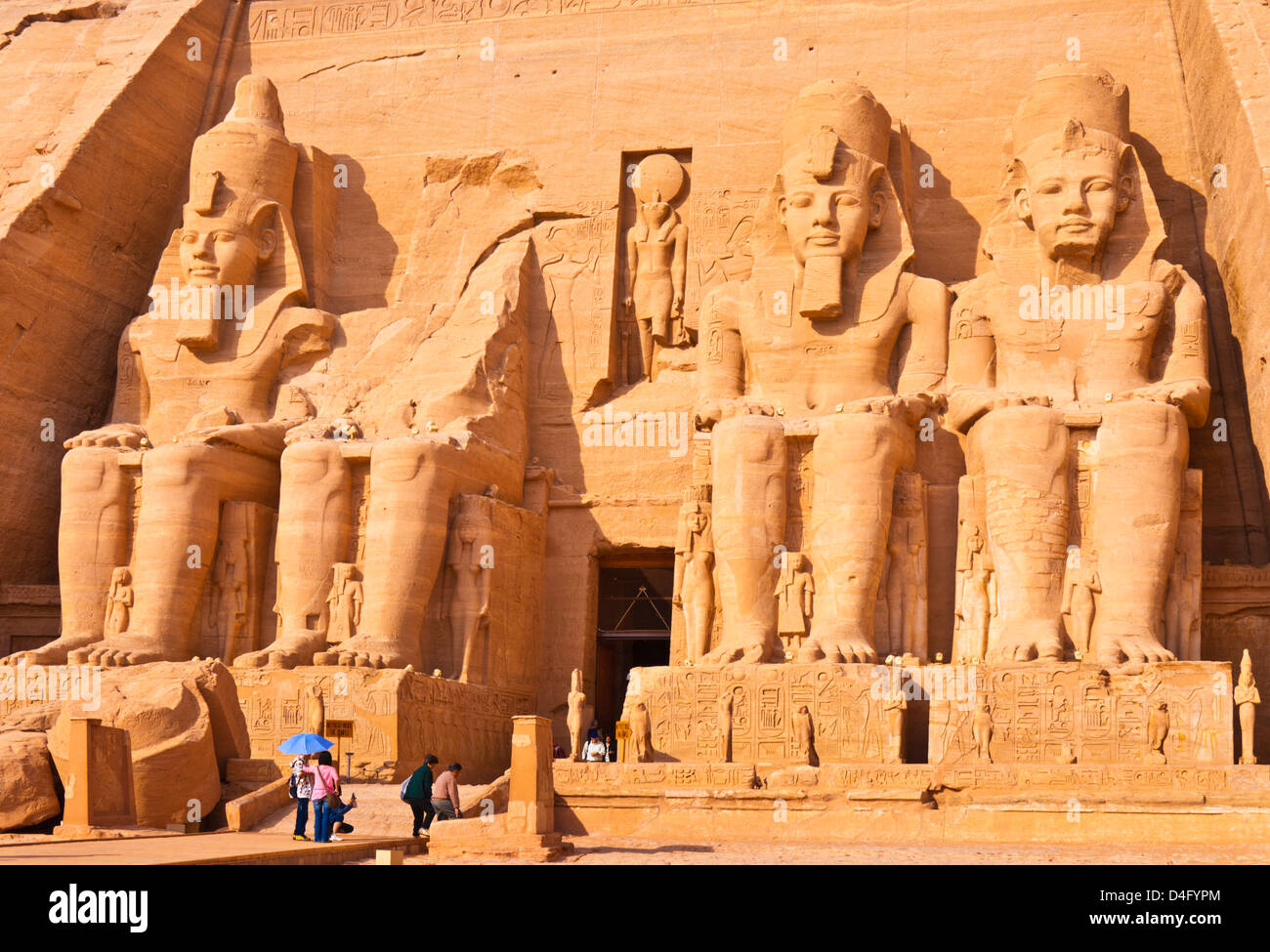 Turisti di viaggi al di fuori dell'ingresso del Grande Tempio di Ramses II Abu Simbel Aswan Egitto Medio Oriente Foto Stock