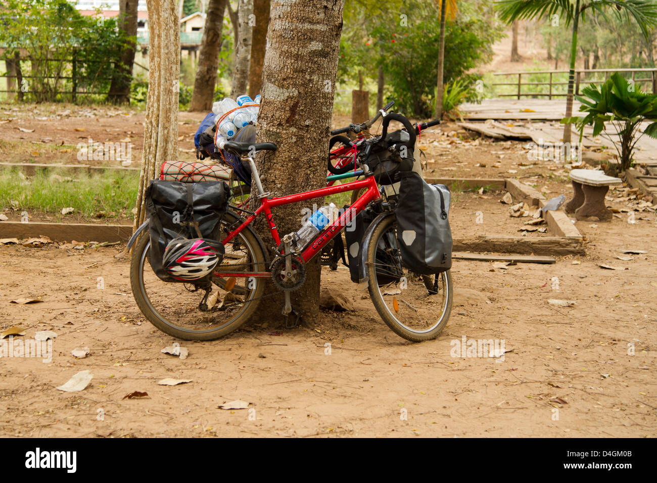 Un molto carico touring bike si appoggia contro un albero Foto Stock