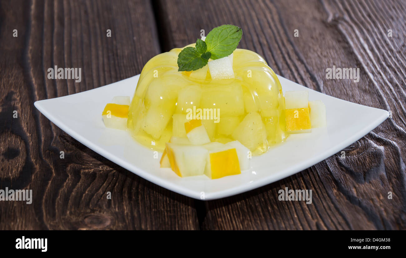 In casa di melata jella con pezzi di frutta su sfondo di legno Foto Stock