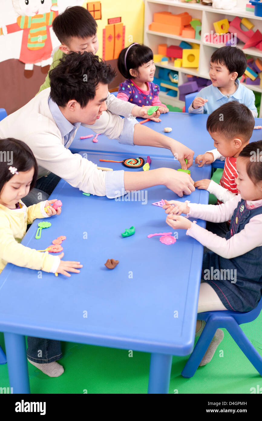 Insegnante di scuola materna e bambini che giocano con il gioco del bambino creta Foto Stock