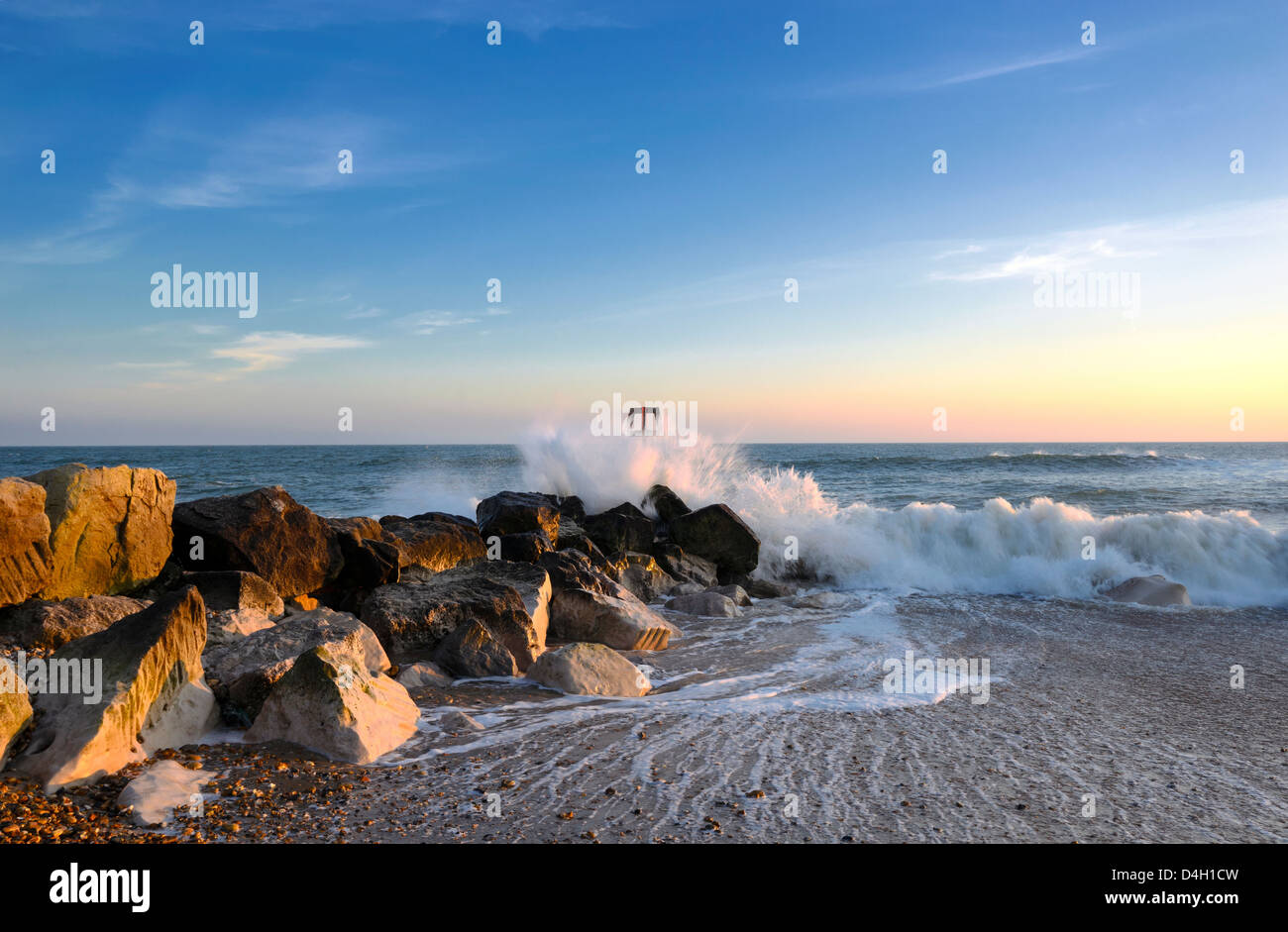 Forme d'onda colpendo un mare groyne e rocce sulla spiaggia a testa Hengistbury vicino a Bournemouth in Dorset Foto Stock