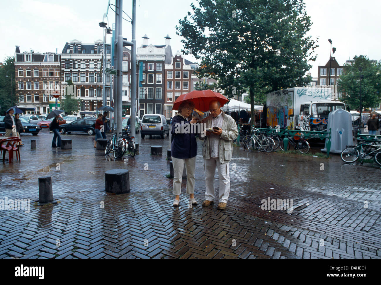 Amsterdam Olanda giovane sotto la pioggia con ombrello Guardando il Libro Guida Foto Stock