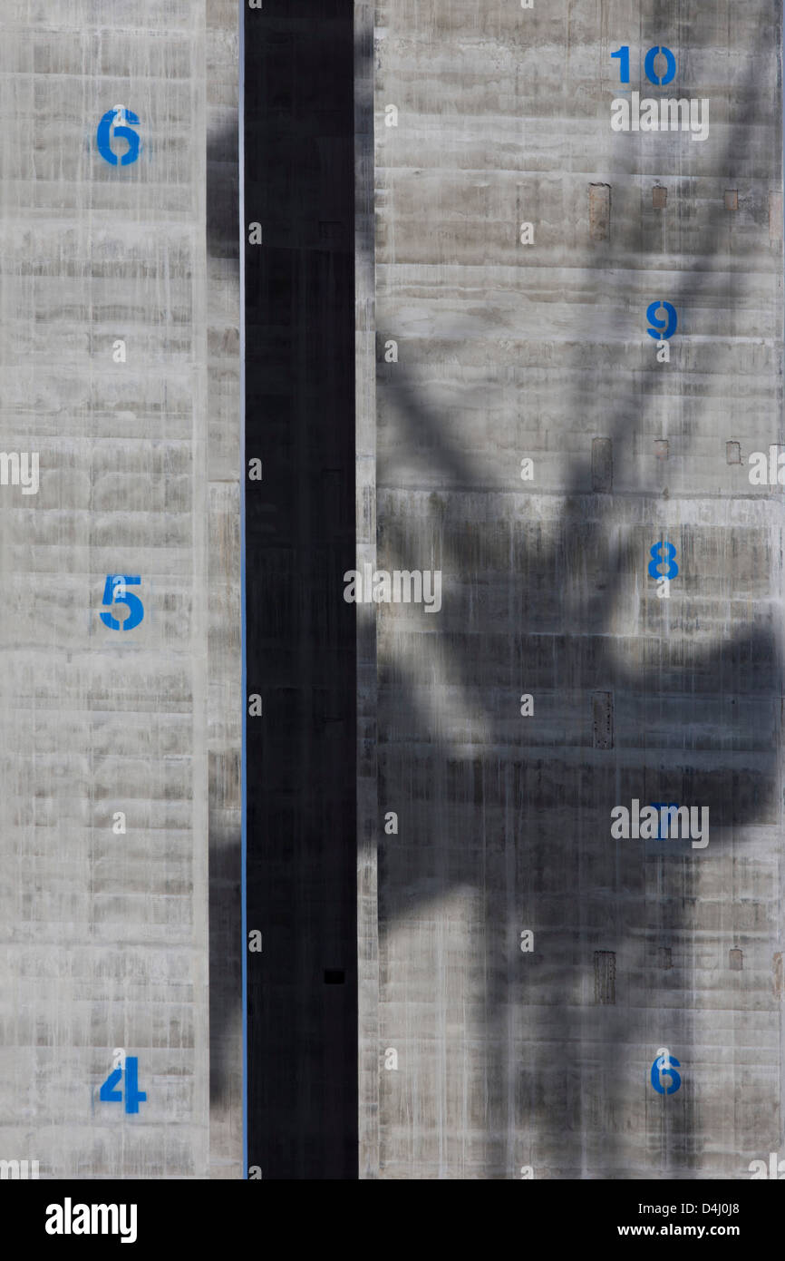 L ombra di una gru è sparso su tutta la superficie in calcestruzzo di un albero di sollevamento con i loro piani contrassegnati verticalmente a 5 Broadgate, progettato da rendere gli architetti che diventerà la nuova casa di UBS a Londra quando è completamente occupata. Salendo verso il cielo è la torre-come struttura con numeri di blu di futuri piani, impresse su al grigio cemento armato. Foto Stock