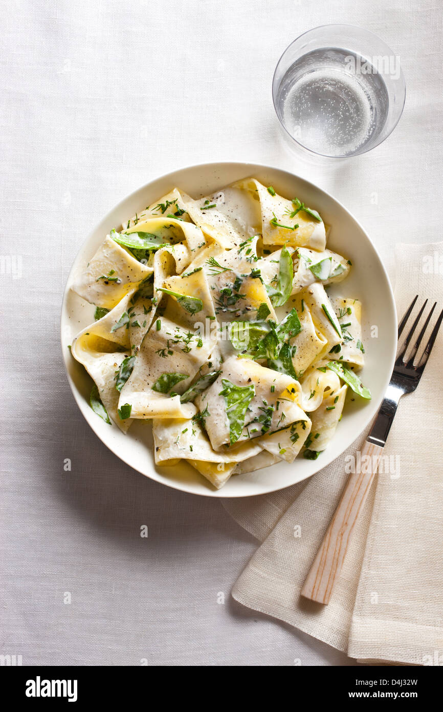 Un piatto di pappardelle con crema di ricotta, baby spinaci erbe fresche e pepe nero. Foto Stock