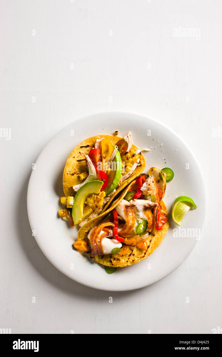 Shredded Tacos di pollo con pomodori, avocado e mais alla Griglia + Sauté di Tilapia Tacos con peperoni colorati e grigliate di cipolla. Foto Stock