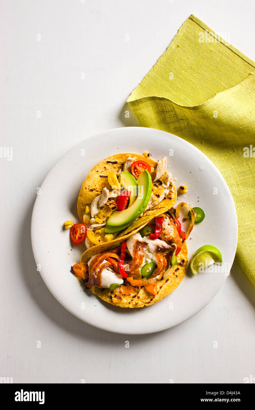 Shredded Tacos di pollo con pomodori, avocado e mais alla Griglia + Sauté di Tilapia Tacos con peperoni colorati e grigliate di cipolla. Foto Stock