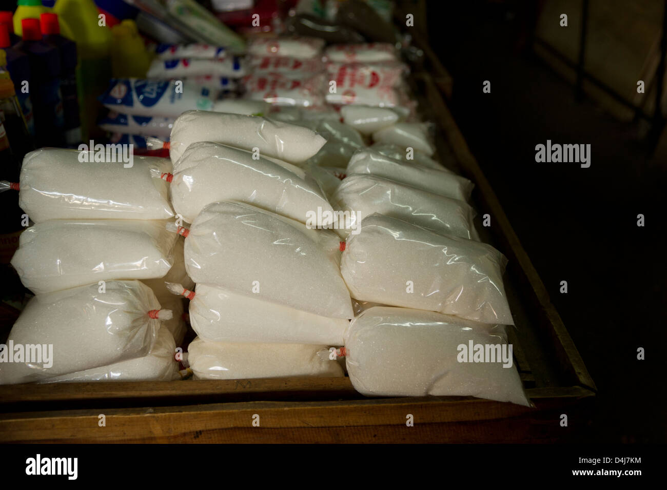 Una busta di plastica trasparente di zucchero di sedersi in una pila su un tavolo in un mercato Foto Stock