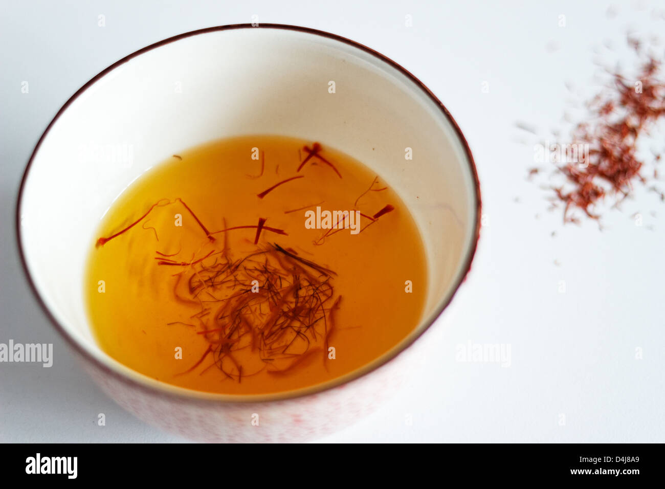 I fili di zafferano in ammollo una tazza di acqua Foto Stock