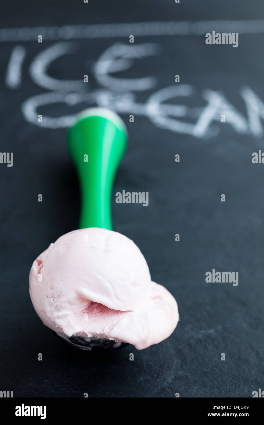 Vista dettagliata del gelato alla fragola e scoop su sfondo scuro con il testo scritto in Chalk Foto Stock