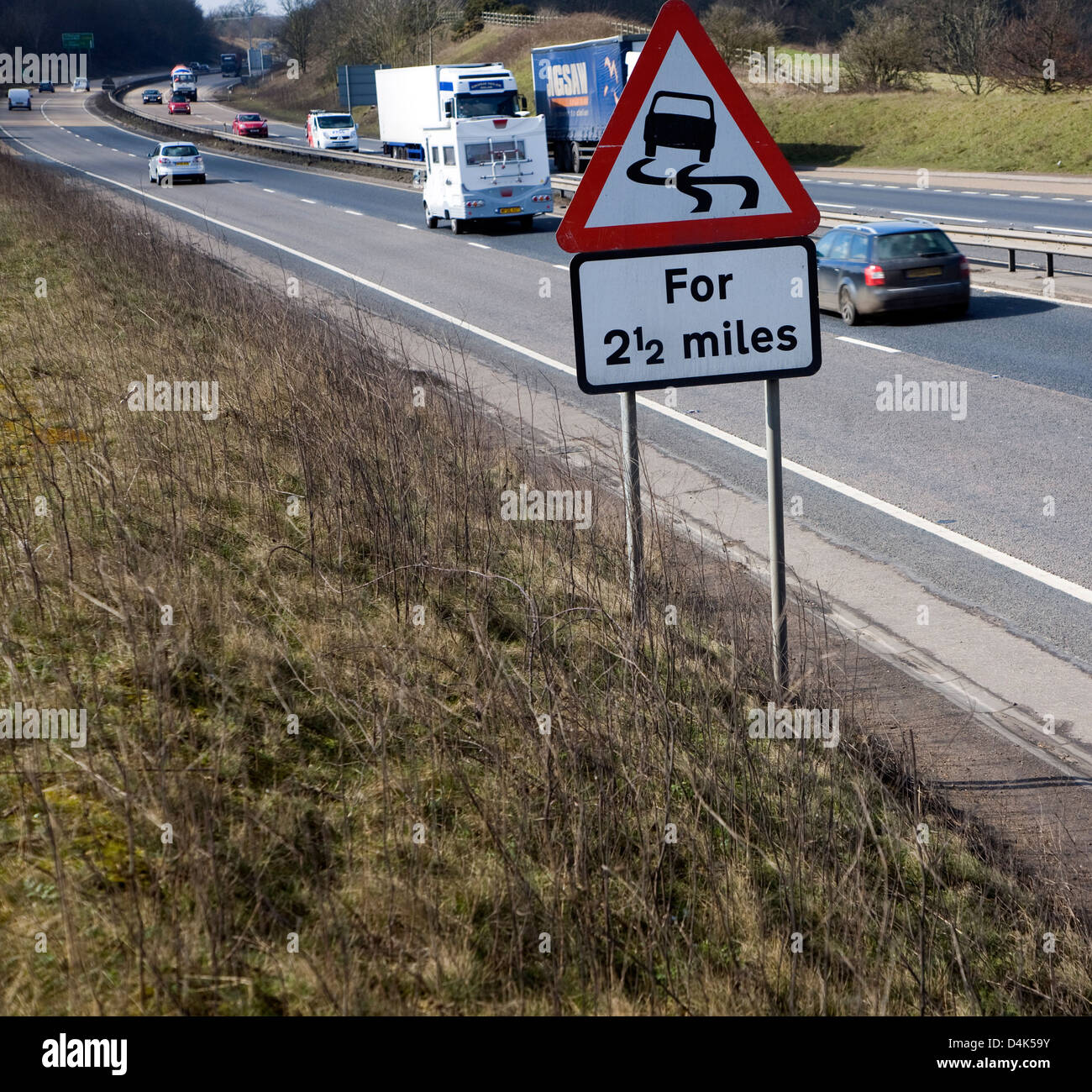 Triangolo rosso cartello stradale di avvertimento di angoli A14 trunk Road, Ipswich Suffolk, Inghilterra. Foto Stock