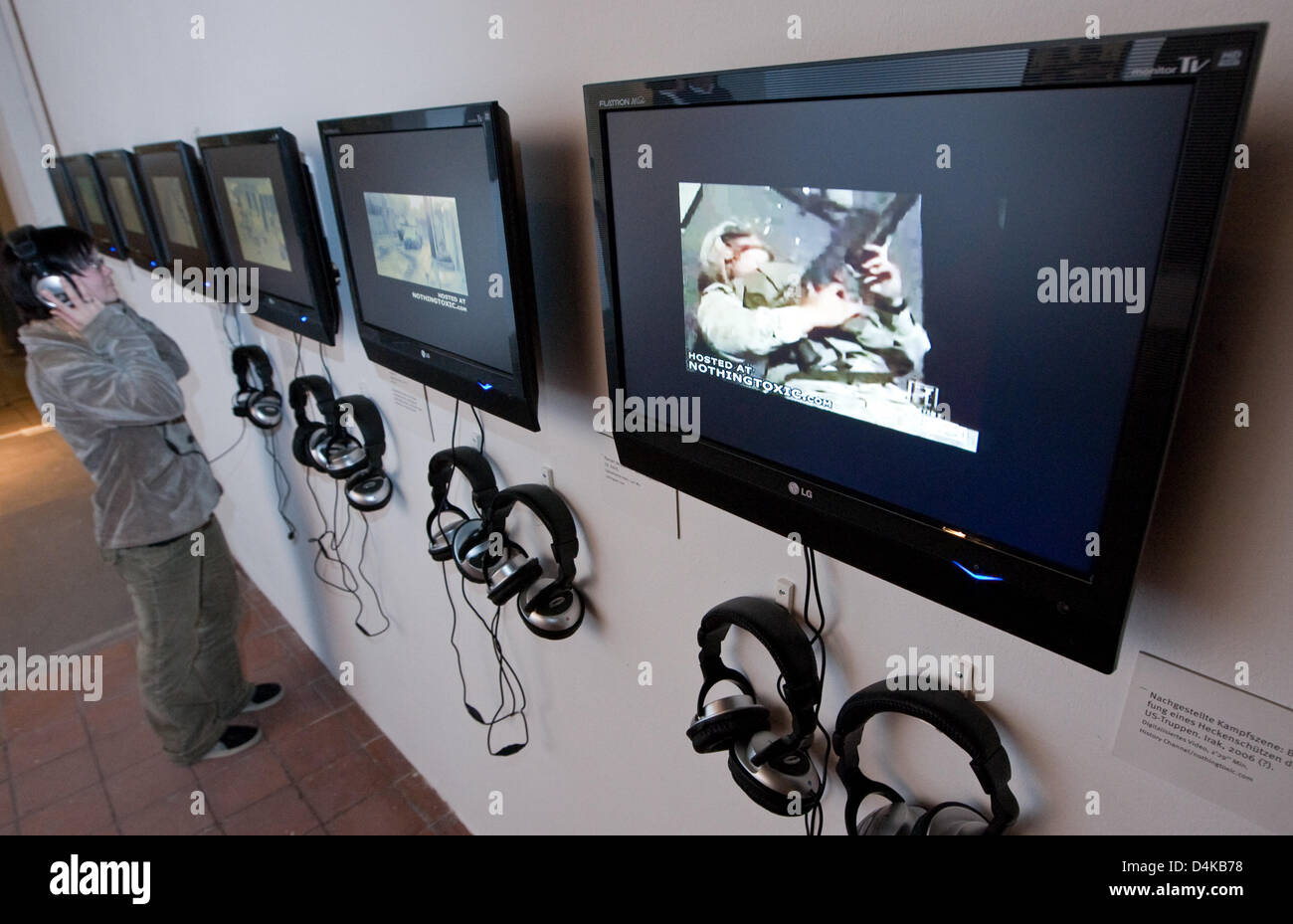 Un visitatore esamina le installazioni video di Thomas Schneider sul display nell'ambito della mostra ?Bilderschlachten? (?Battaglie immagine?) a ?Kunsthalle Dominikanerkirche? A Osnabrück, Germania, 21 aprile 2009. Le schermate mostrano la reale e unreal scene di battaglia che coinvolgono i soldati USA in Iraq. Bilderschlachten ?? Mostra si svolge in collaborazione con la European Media Art Festiv Foto Stock