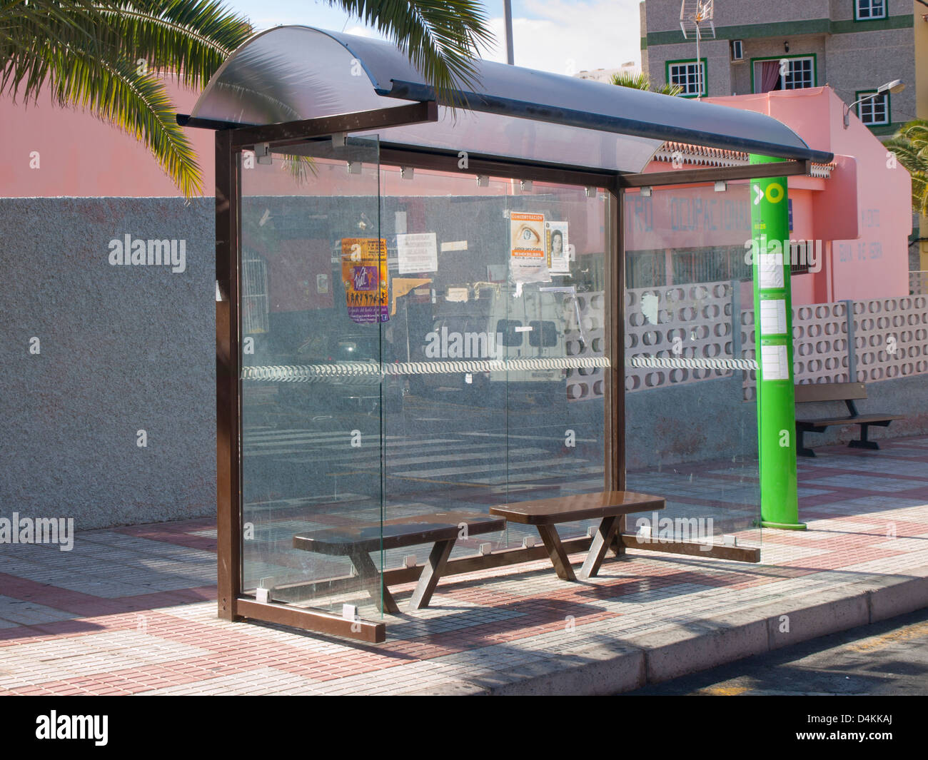 Fermata bus capannone con posti a sedere e informazioni su un marciapiede in Tenerife Spagna.Bus Company logo Titsa, colore verde, con orari Foto Stock