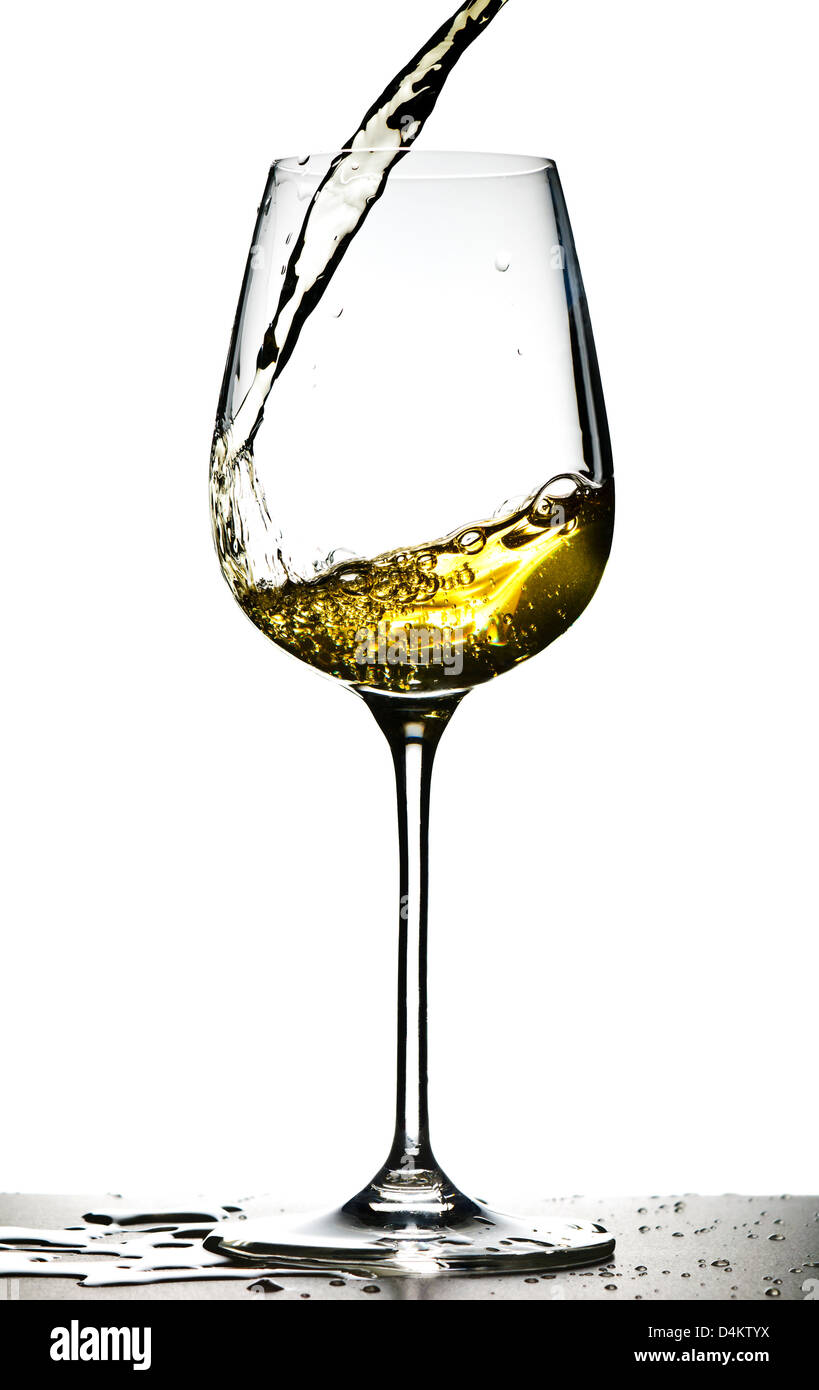 Vetro con versando il vino bianco su sfondo bianco Foto Stock
