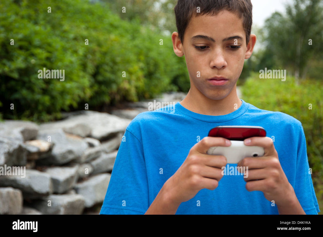 Ragazzo giovane texting sul suo telefono cellulare Foto Stock