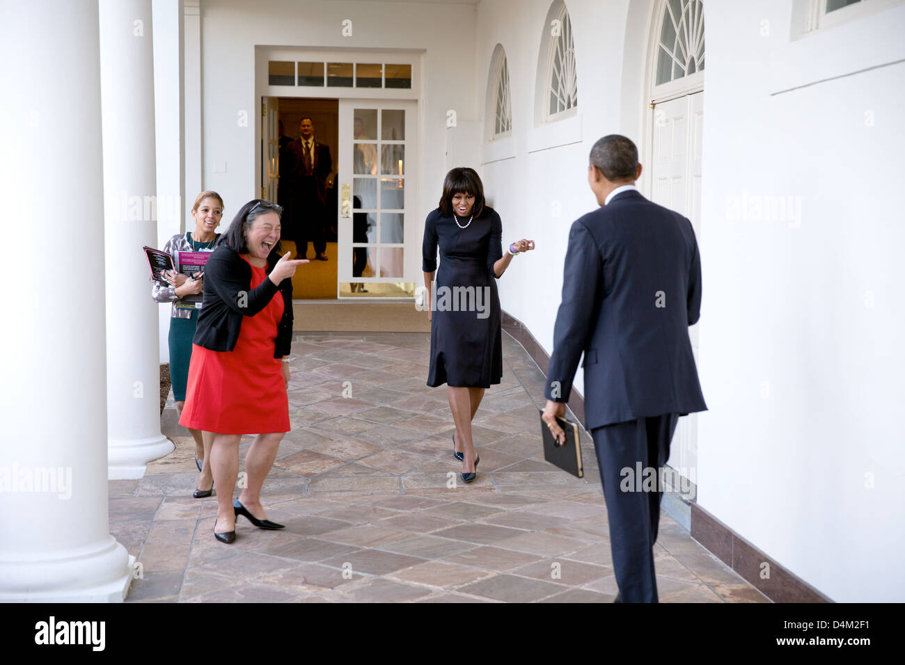 Il Presidente Usa Barack Obama orologi come la First Lady Michelle Obama scherzosamente saluta su di lui il colonnato della Casa Bianca Febbraio 12, 2013 a Washington, DC. Tina Tchen, Capo del personale alla First Lady e Personal Aide Kristin Jones, sinistra, accompagnare la sig.ra Obama. Foto Stock