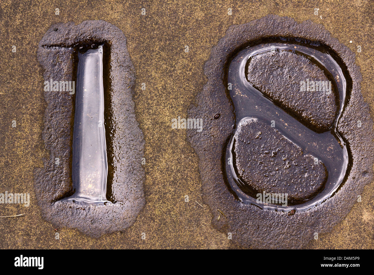 Vecchio riempito di acqua in pietra scolpita 18 numero di diciotto in lastricato all'esterno la chiesa di San Martino, Stamford, Lincolnshire, England, Regno Unito Foto Stock