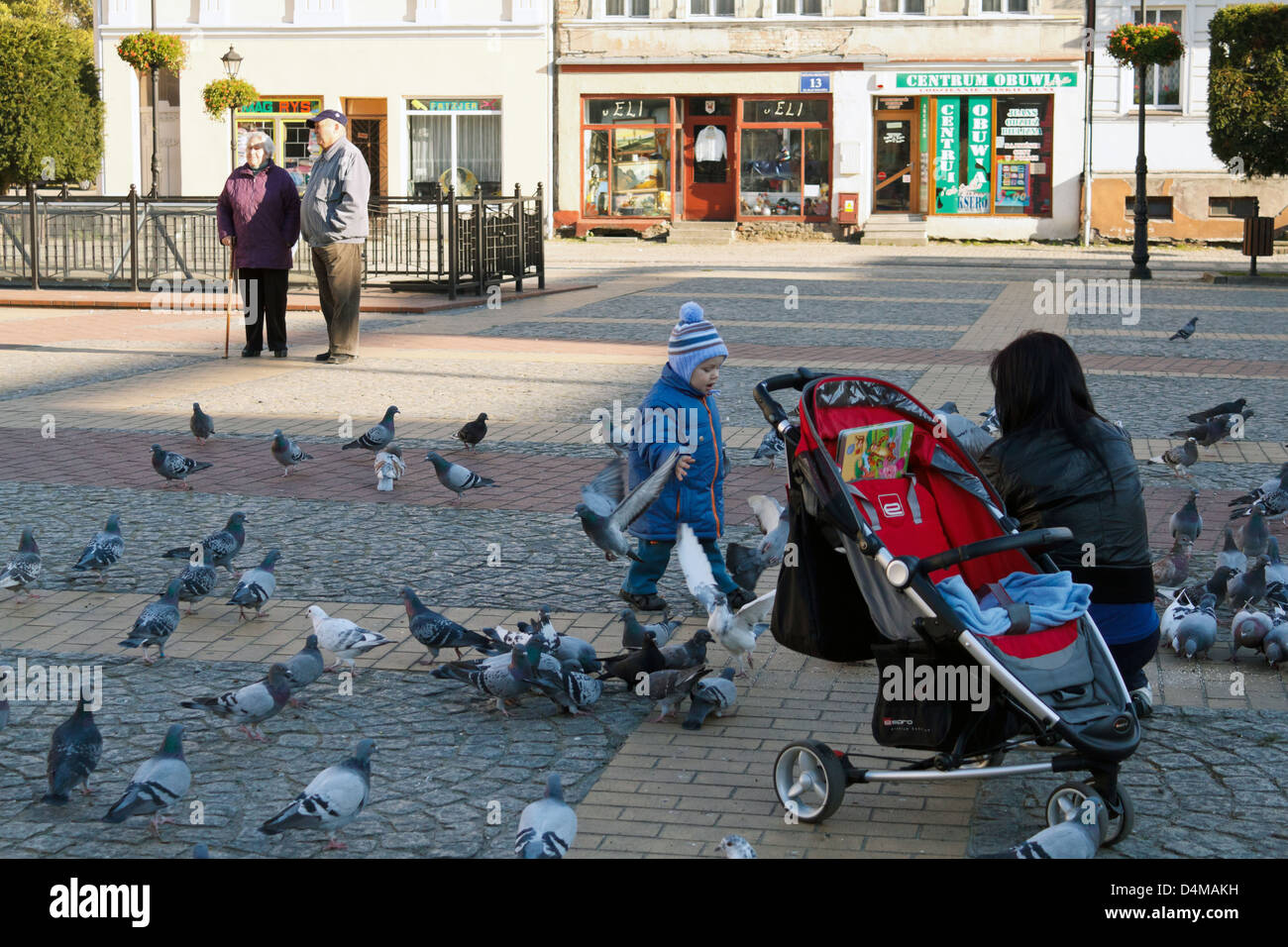 Belgard a Persante, Polonia, una donna alimentare piccioni in Piazza Foto Stock