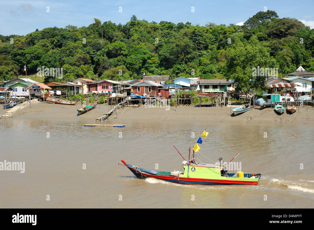 Tradizionale barca sul fiume in legno che attraversa un villaggio costiero di Malay Stilt e la foresta pluviale di Lowland vicino al Parco Nazionale di Bako Sarawak Borneo Malesia Foto Stock
