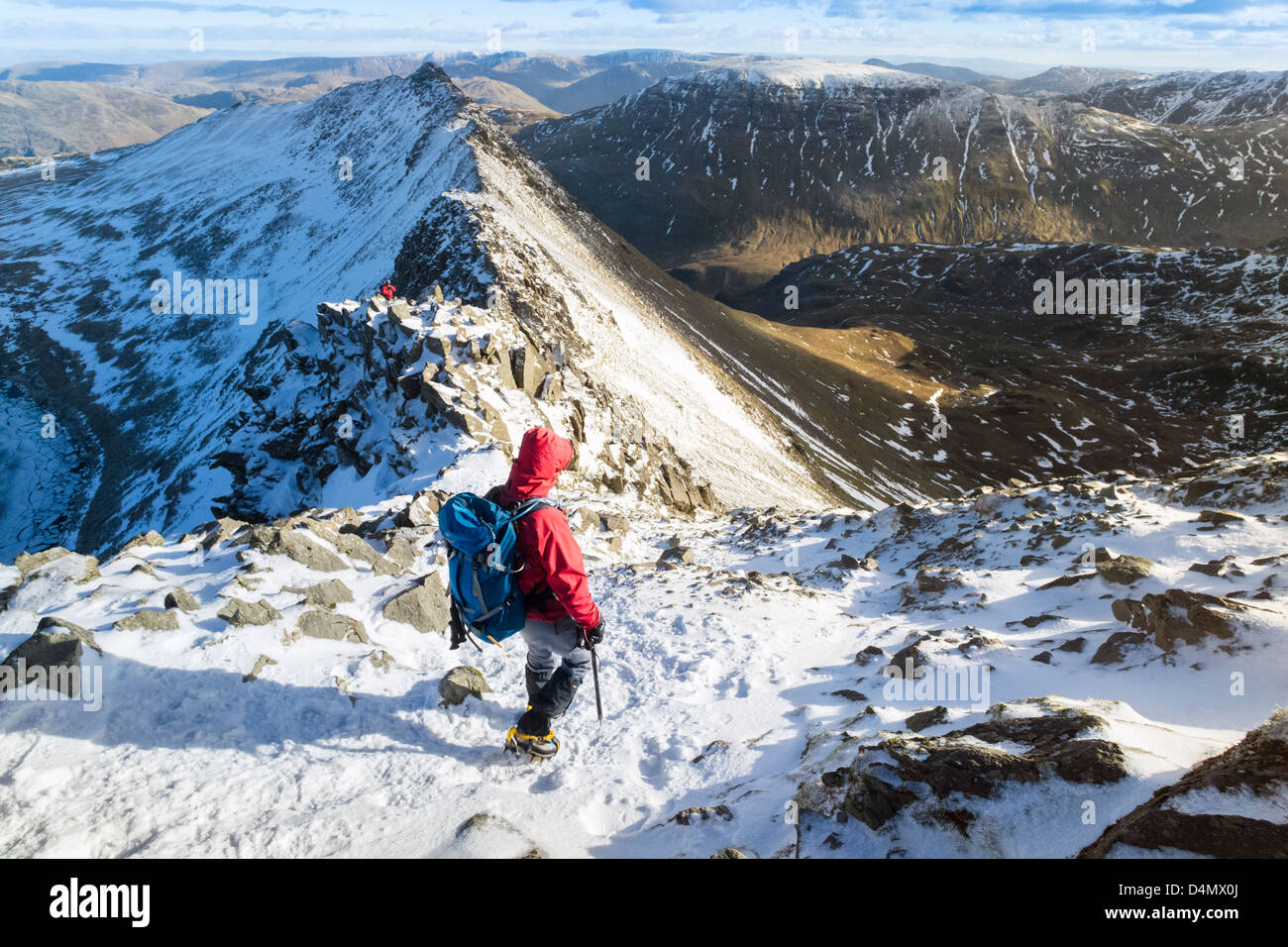 Un escursionista Helvellyn decrescente verso il bordo di estensione e Red Tarn nel distretto del lago. Foto Stock