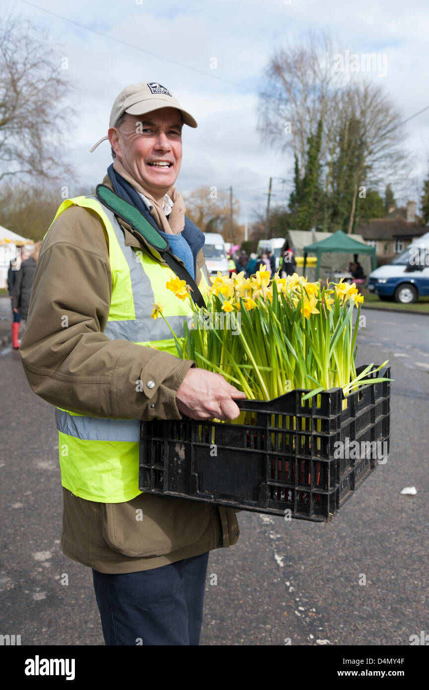 Thriplow Daffodil Weekend, Cambridgeshire, Regno Unito. Sabato 16 marzo 2013. Tim Holmes , Presidente del Comitato Daffodil porta un vassoio di vasi di narcisi. La maggior parte delle piantate narcisi hanno ancora a fiore a causa della molla a freddo. Il vento e la pioggia non ha impedito il festival annuale che è frequentato da migliaia di visitatori e continua domani. La manifestazione è organizzata dall'Daffodil Weekend fiducia e raccoglie fondi per una diversa carità ogni anno. Credito: Julian Eales / Alamy Live News Foto Stock Thriplow Daffodil Weekend, Cambridgeshire, Regno Unito. Sabato 16 marzo 2013. Tim Holmes , Presidente del Comitato Daffodil porta un vassoio di vasi di narcisi. La maggior parte delle piantate narcisi hanno ancora a fiore a causa della molla a freddo. Il vento e la pioggia non ha impedito il festival annuale che è frequentato da migliaia di visitatori e continua domani. La manifestazione è organizzata dall'Daffodil Weekend fiducia e raccoglie fondi per una diversa carità ogni anno. Credito: Julian Eales / Alamy Live News Foto Stock