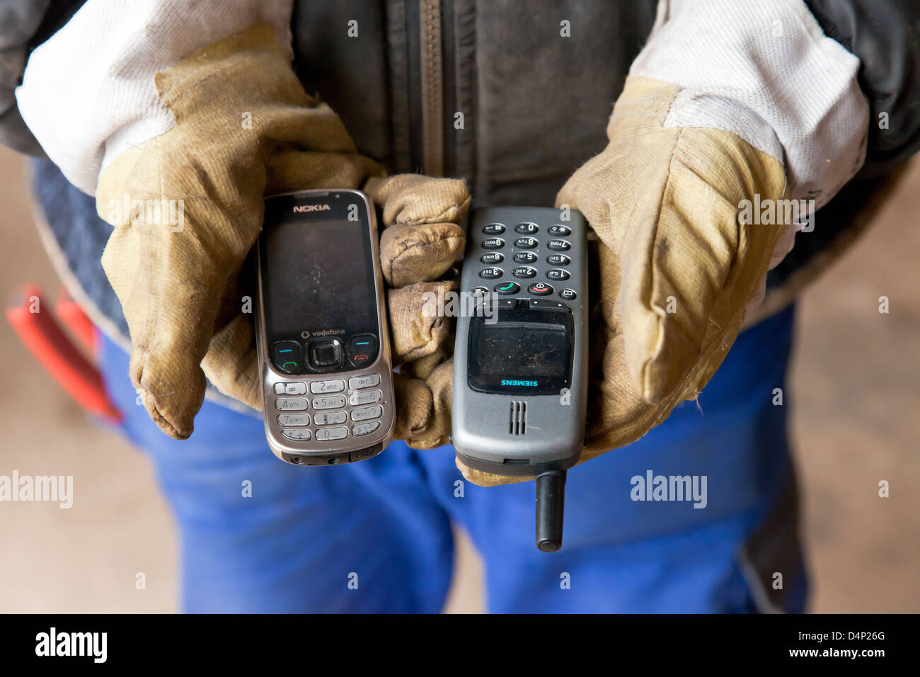Berlino, Germania, il dipendente detiene BRAL vecchi telefoni cellulari nelle mani Foto Stock