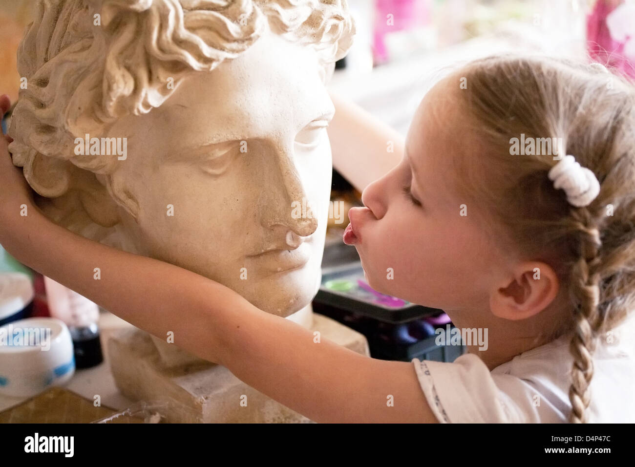 Piccola ragazza baciare la testa di antica statua romana Foto Stock