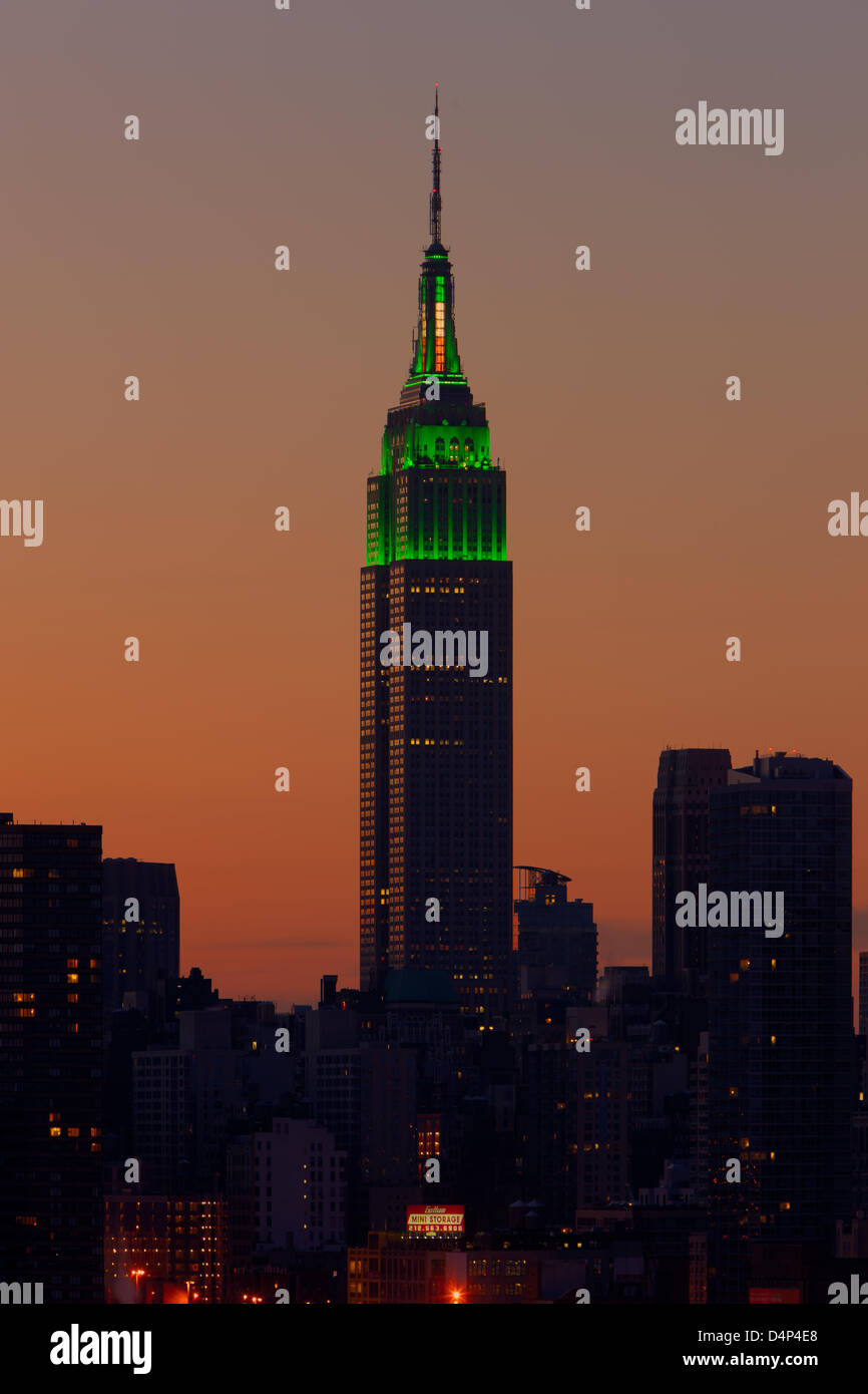 L'Empire State Building è illuminato in verde si accende come il cielo si illumina di arancione prima del sorgere del sole in New York City. Foto Stock