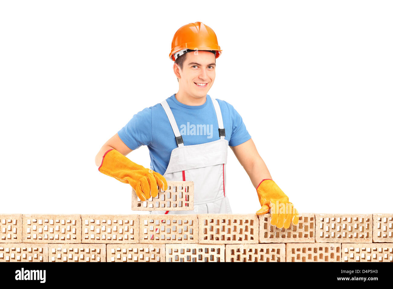 Costruzione maschio lavoratore tenendo un mattone dietro un muro di mattoni isolati su sfondo bianco Foto Stock