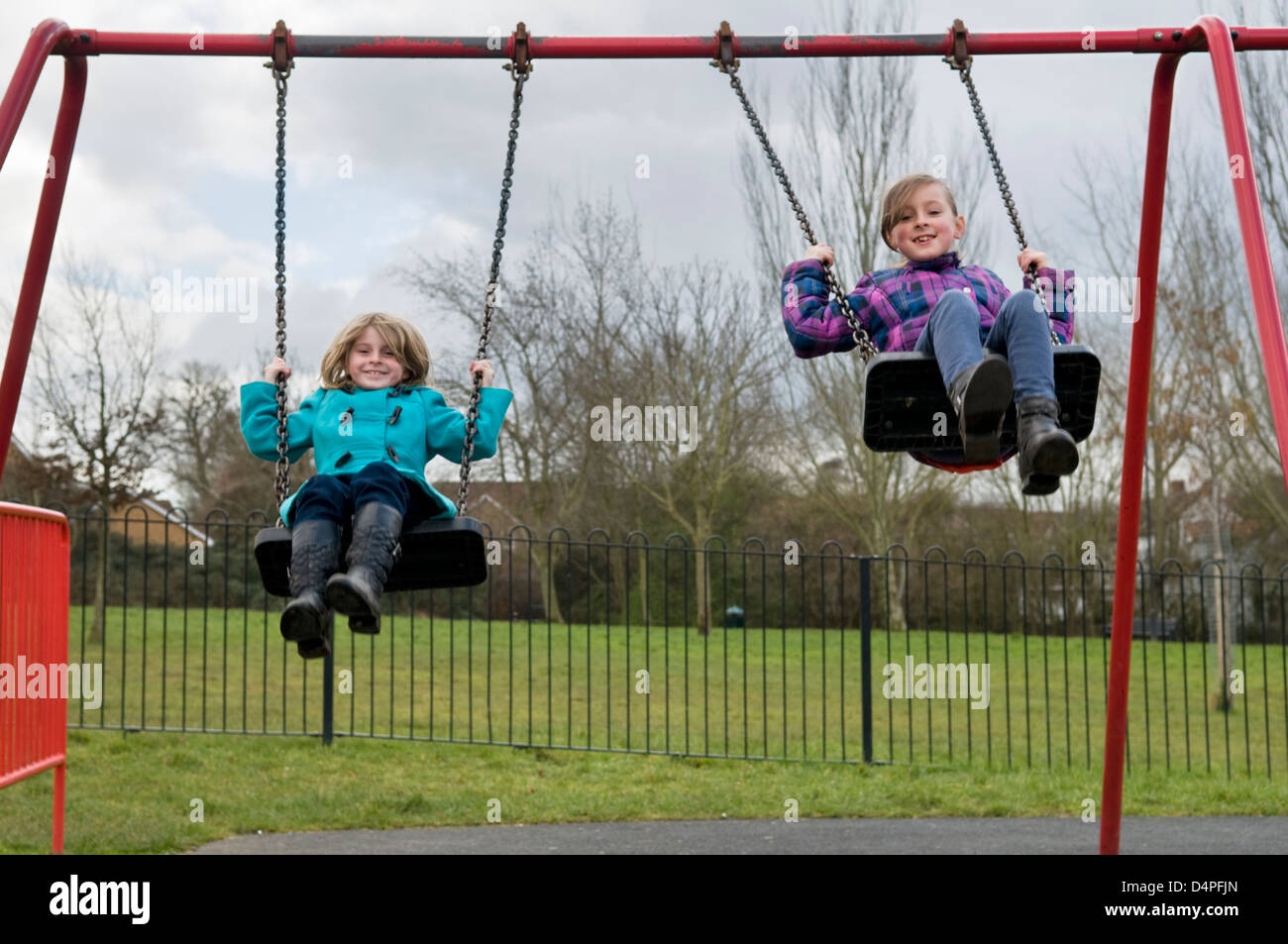 Due di 8 anni ragazze caucasica divertirsi giocando sulle altalene nel parco in Bristol, Regno Unito Foto Stock