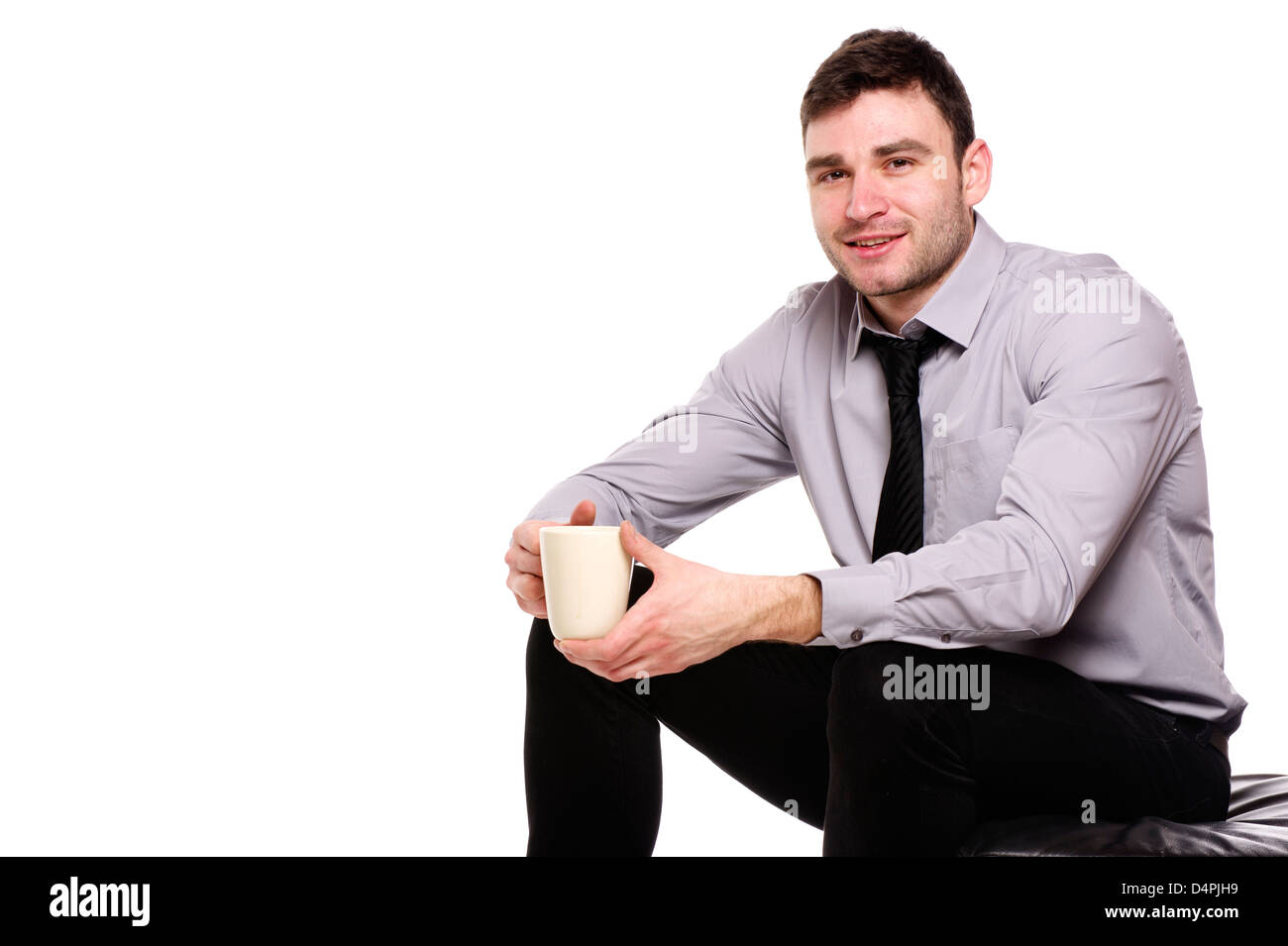 Bello il business man sat isolato su uno sfondo bianco tenendo una tazza di caffè Foto Stock